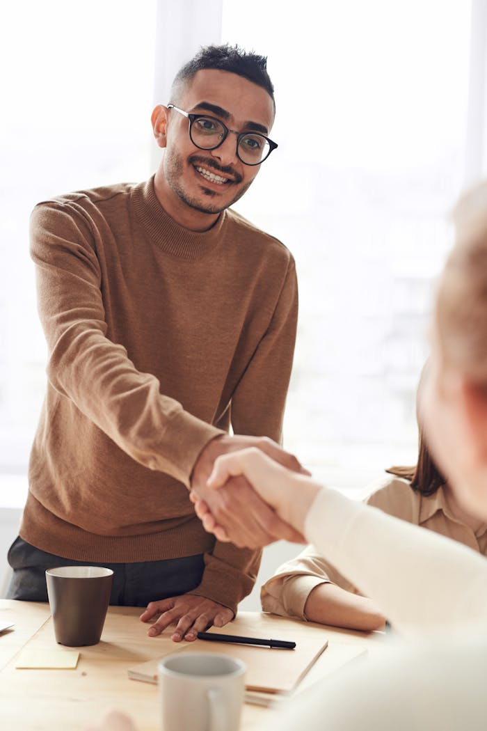 services-02 Smiling professionals engage in a welcoming handshake at a business meeting indoors.